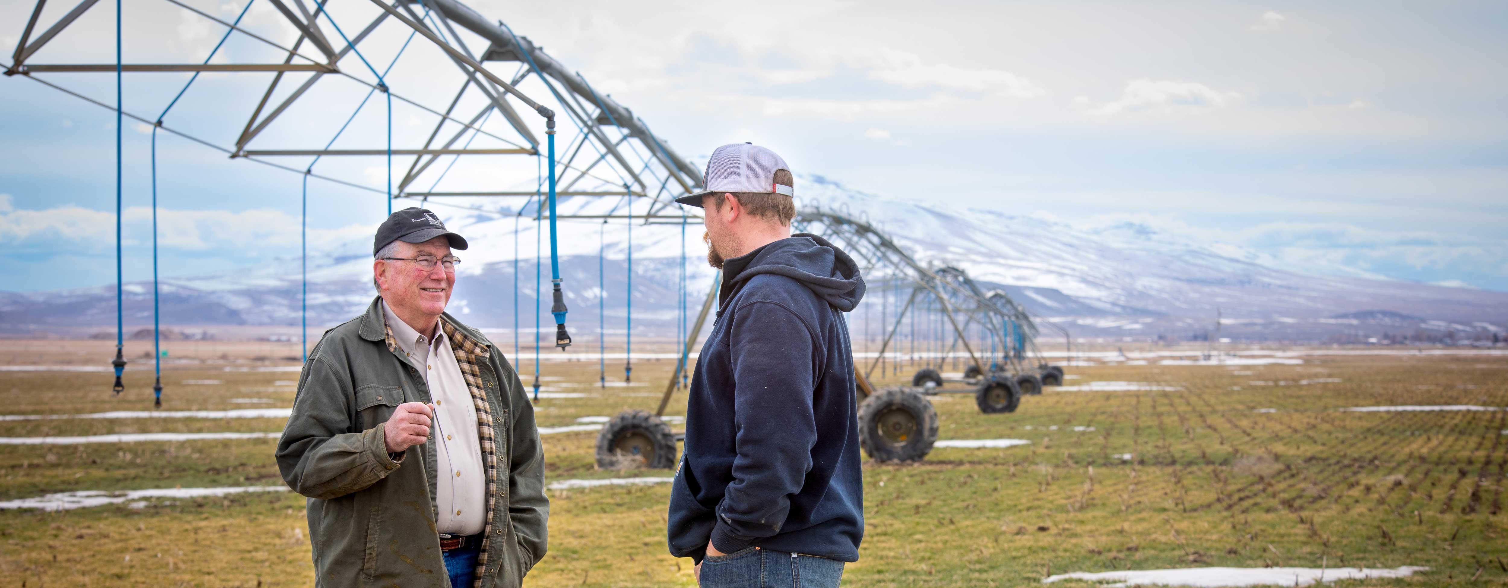 Scott Bedke speaking with person in front of a pivot irrigation in a field